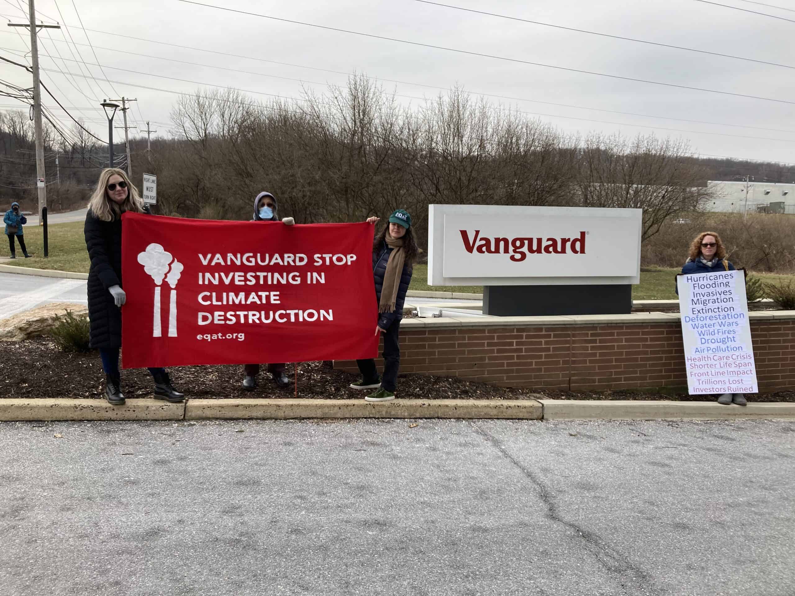 Four people standing in front of Vanguard sign with banner syaing "Vanguard Stop Investing in Climate Destruction."